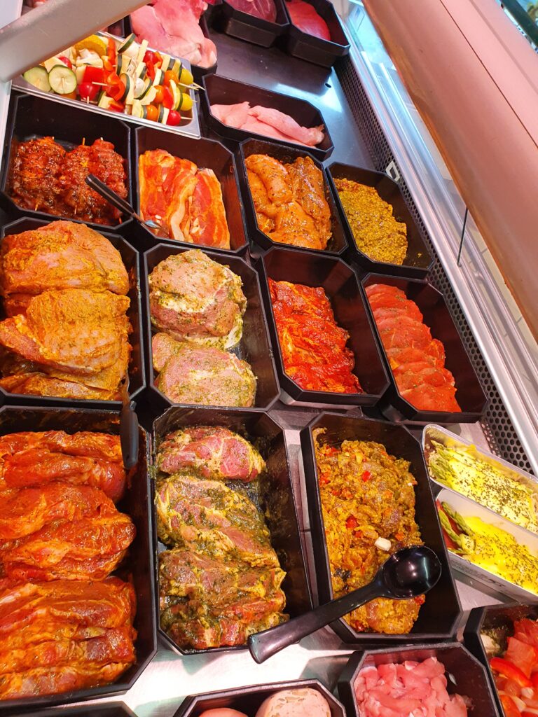 Grilltheke mit mariniertem Fleisch in Schalen