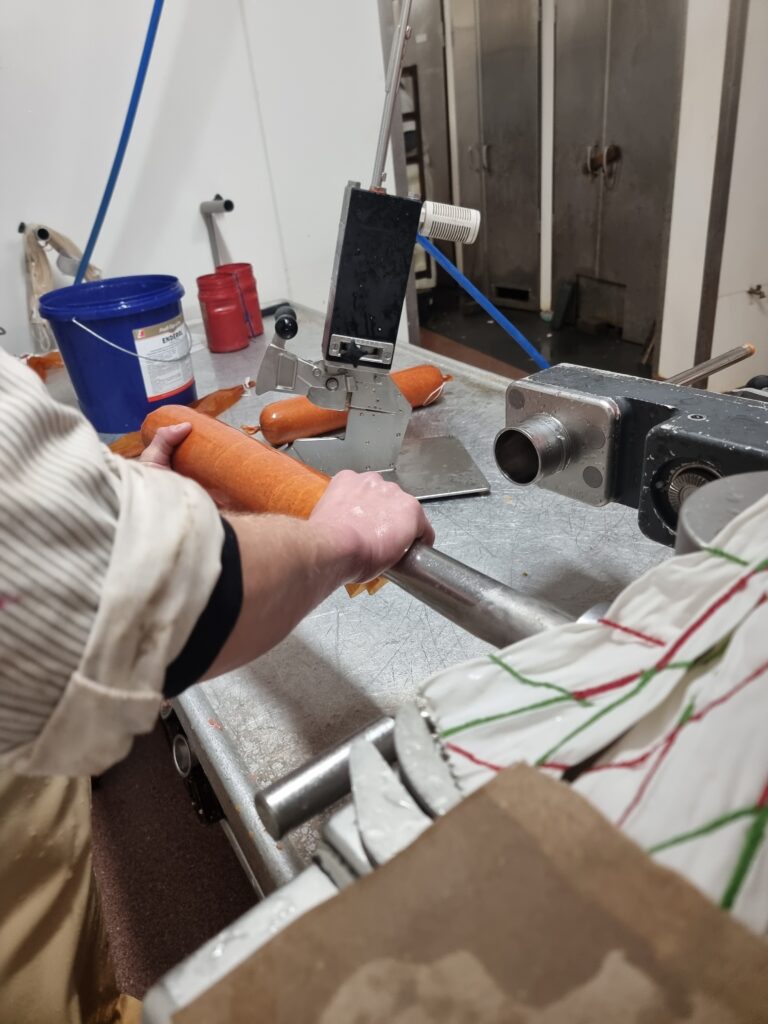 Wurst wird von Hand in der Wurstküche abgefüllt